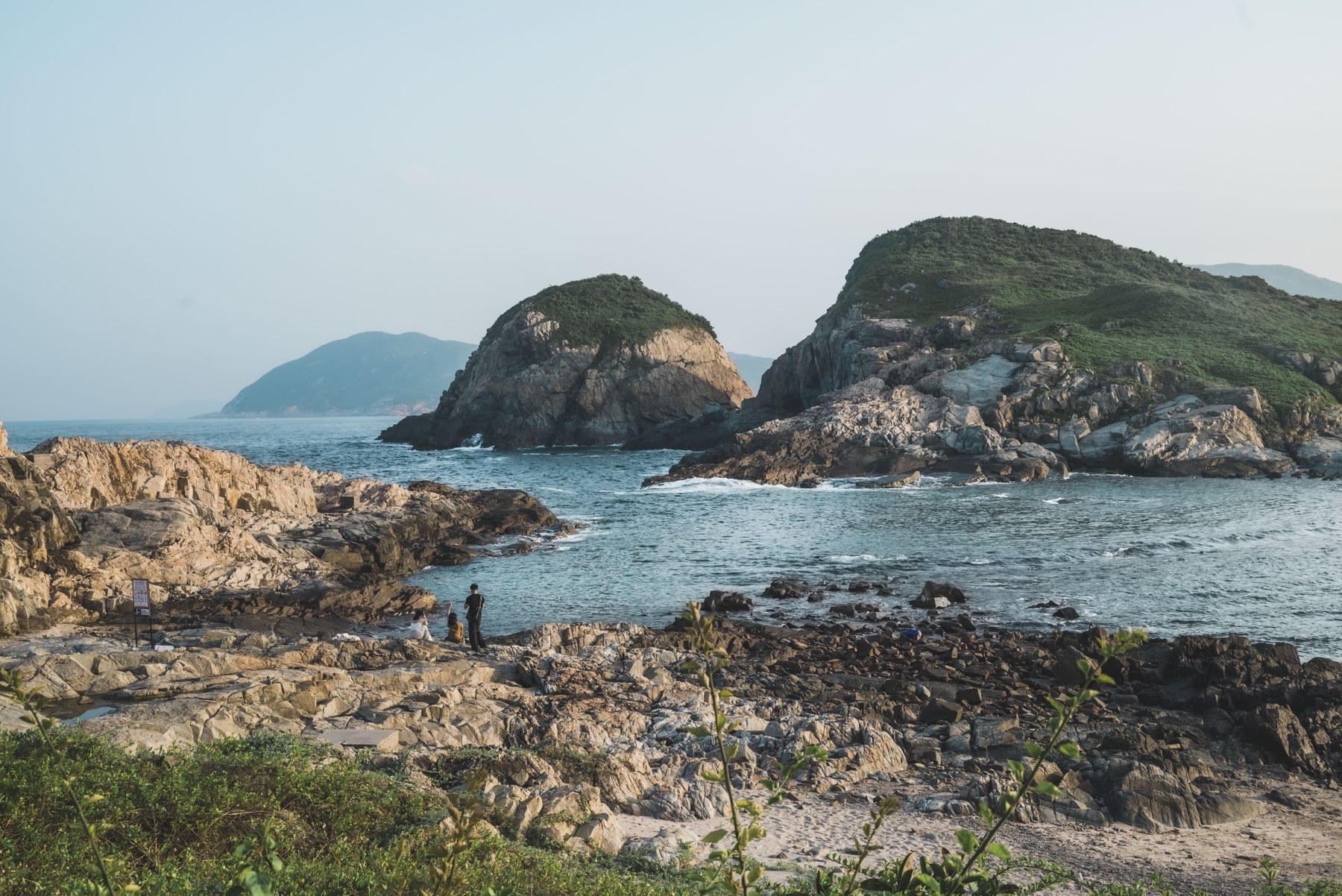 香港 · 岩岸、海水与游人构成多层海边景象。
