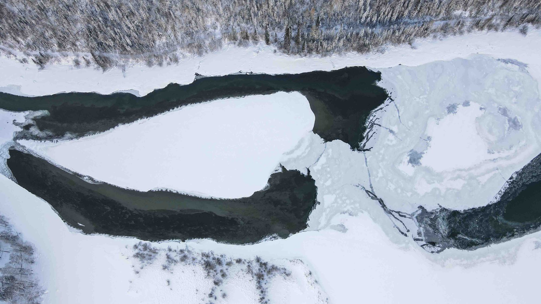 阿勒泰喀纳斯河航拍 · 深色河道在白雪间蜿蜒,形成鲜明的线条与留白。